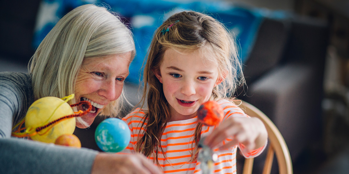 Grandmother and granddaughter playing with planet toys