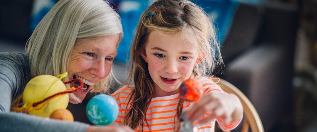 Grandmother and granddaughter playing with planet toys