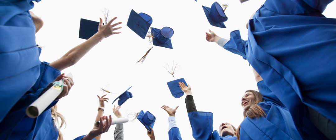 Graduates throwing mortar boards in the air