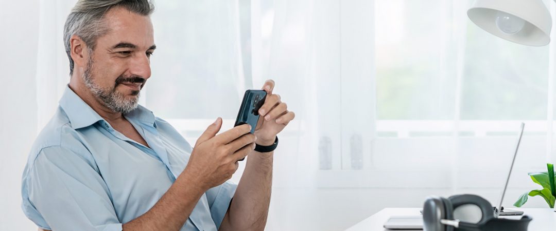 Man sitting at a desk looking at his phone